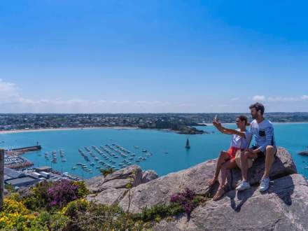 Un couple de vacanciers du camping Saint Pabu Plage admire ce petit coin de paradis assis sur un rocher du port d'Erquy.